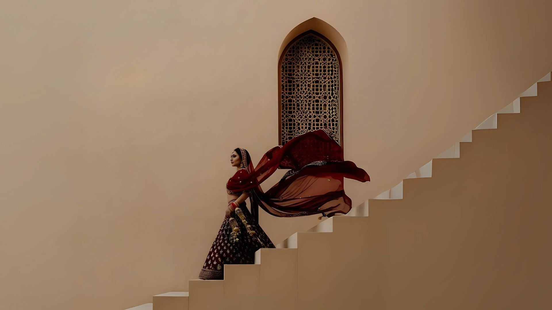 Woman in traditional attire descending a staircase with a flowing fabric.